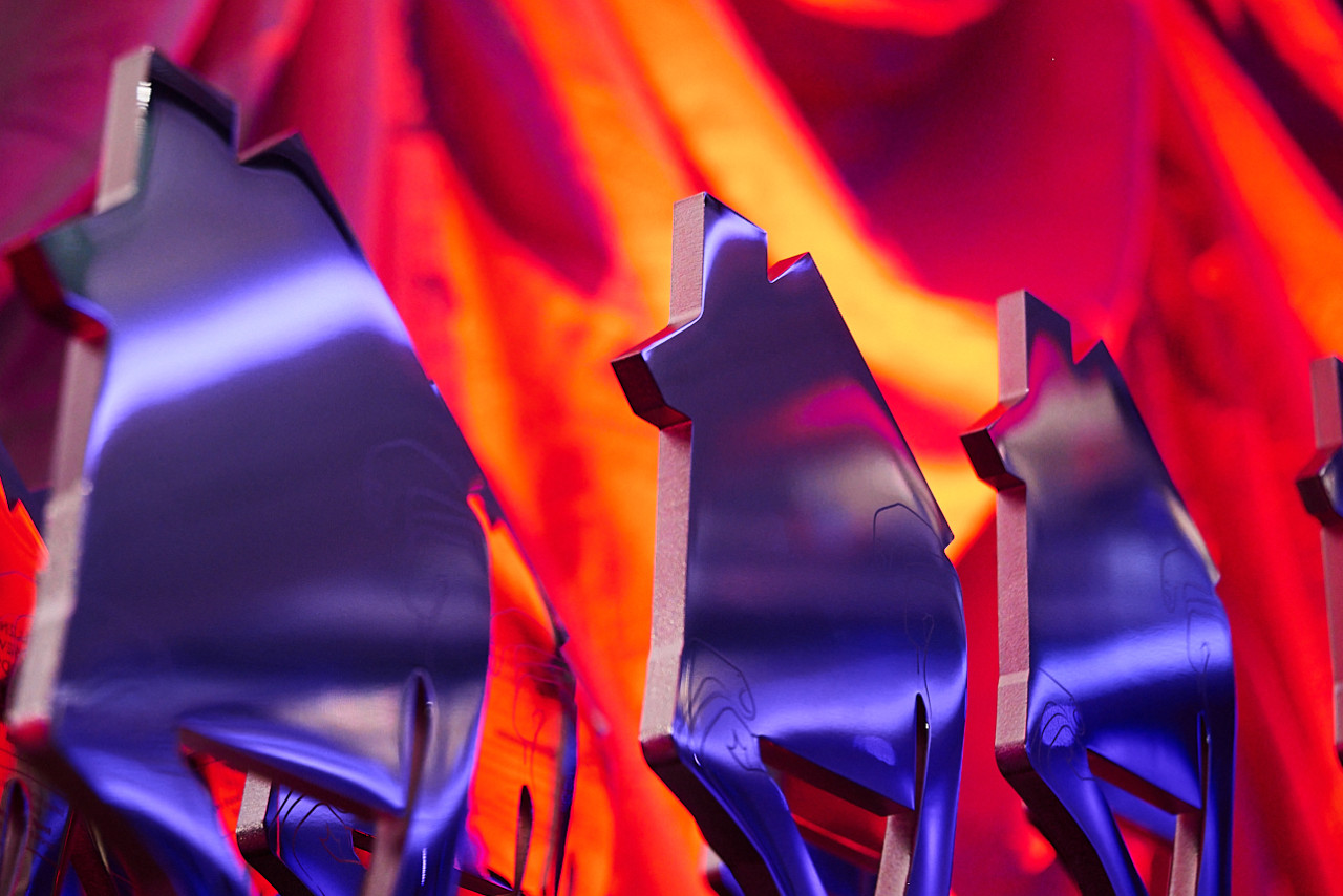 Shiny silhouette trophies shaped like animals stand in a row against a vibrant, colorful backdrop.