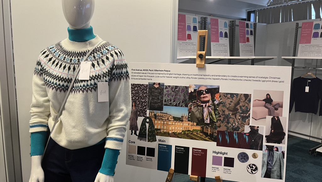 A mannequin displays a stylish winter sweater featuring a blue and white pattern, paired with teal pants. Beside it, a presentation board showcases fabric swatches and design inspirations, highlighting color palettes and styles for a fashion collection.