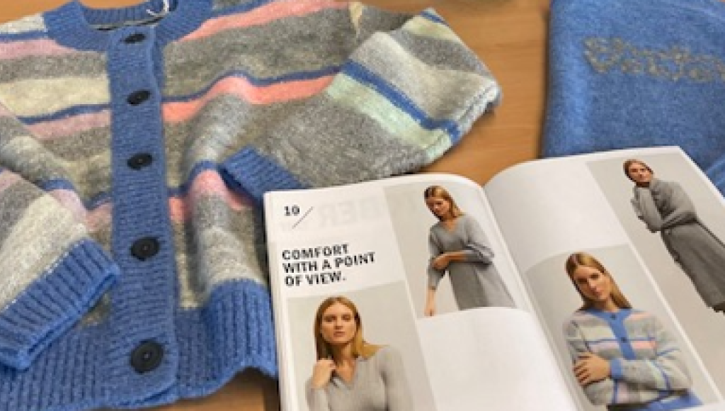 A cozy striped cardigan in shades of blue, pink, and gray, alongside a light blue sweater featuring the text 