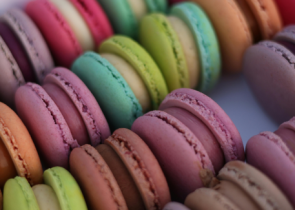 A colorful assortment of macarons arranged in a circular pattern, showcasing various pastel shades like pink, green, orange, and purple.